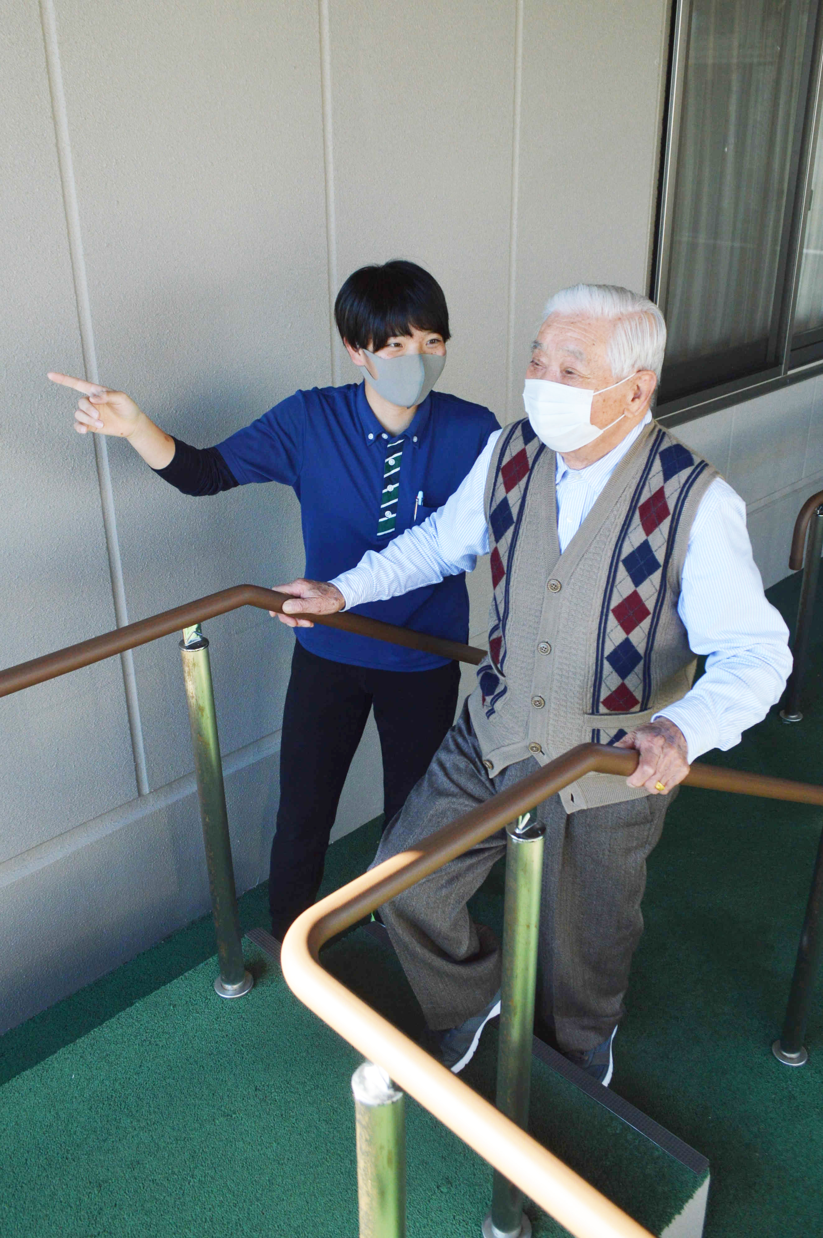 利用者の歩行訓練を補助する高島絢音選手（左）＝２０２１年１２月、磐田市国府台の「磐田ケアセンターそよ風」