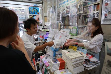 レジで客と和やかに言葉を交わす二村知子さん（右）＝２０２３年１０月、大阪市中央区の隆祥館書店