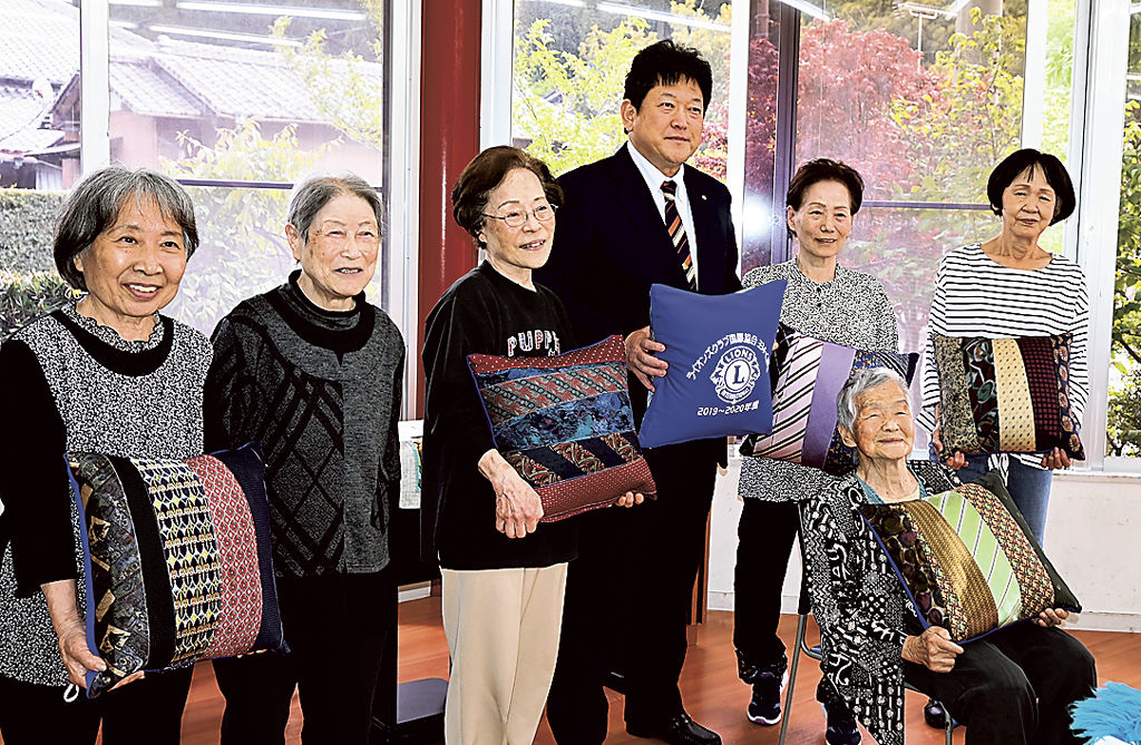 ネクタイを利用したクッションを手にする黒田会長（左から４人目）と利用者＝菊川市棚草の和松園