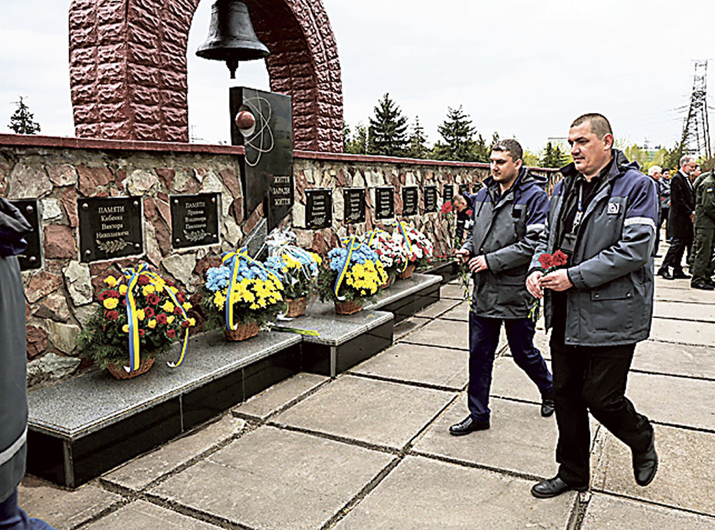 ２６日、ウクライナ北部チェルノブイリ原発敷地内で開かれた記念式典で献花する参加者ら（共同）